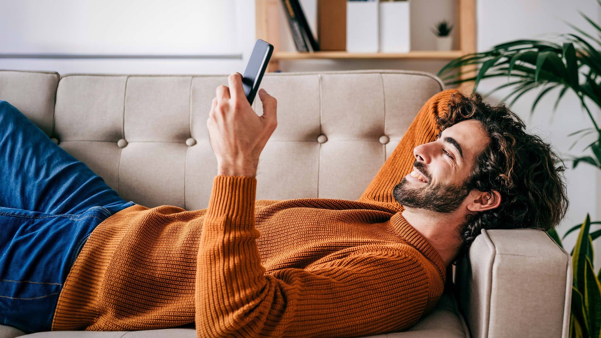 man-couch-phone-happy-hero-16-9-2560x1440px